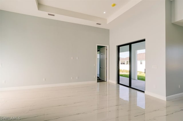 tiled spare room with a high ceiling and a tray ceiling