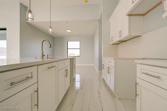 kitchen with hanging light fixtures, sink, light tile floors, and white cabinets