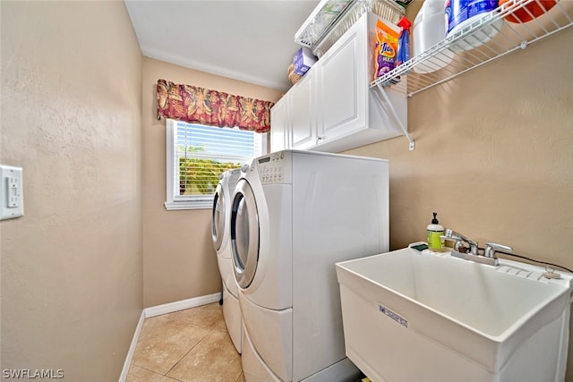 clothes washing area featuring sink, washing machine and dryer, cabinets, and light tile floors