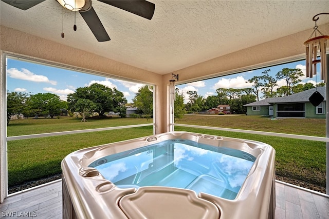 exterior space featuring a hot tub, a yard, and ceiling fan