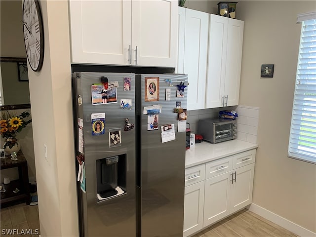 kitchen featuring backsplash, light hardwood / wood-style flooring, white cabinets, and stainless steel fridge