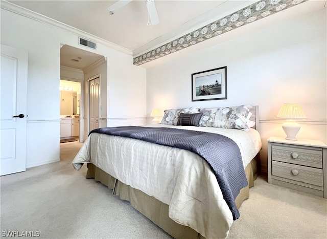 bedroom with light colored carpet, ornamental molding, ceiling fan, and ensuite bath