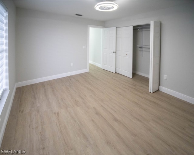 unfurnished bedroom with light hardwood / wood-style flooring and a closet