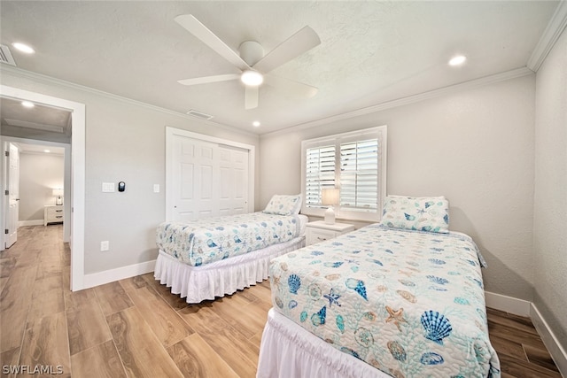 bedroom with crown molding, light hardwood / wood-style floors, ceiling fan, and a closet