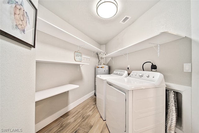 clothes washing area featuring hookup for an electric dryer, light hardwood / wood-style flooring, washer and dryer, and electric water heater