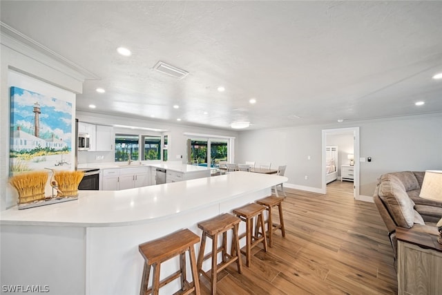 kitchen featuring appliances with stainless steel finishes, a breakfast bar, white cabinets, and light hardwood / wood-style floors