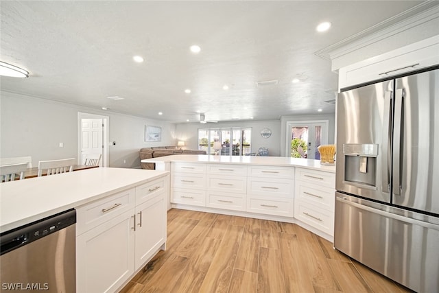 kitchen featuring appliances with stainless steel finishes, crown molding, light wood-type flooring, and white cabinets