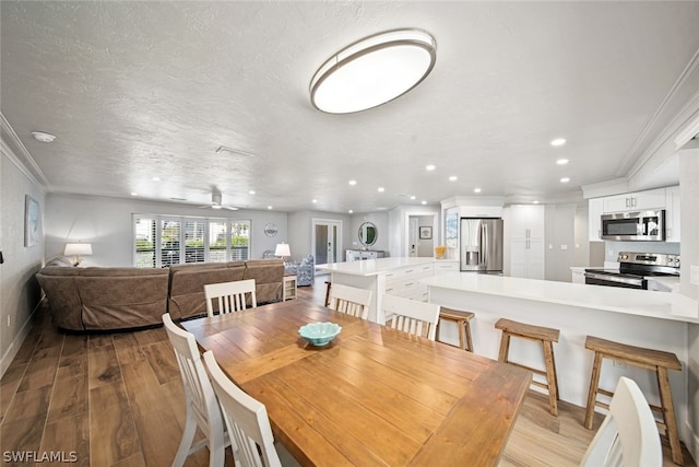 dining space with ornamental molding, light hardwood / wood-style floors, ceiling fan, and a textured ceiling