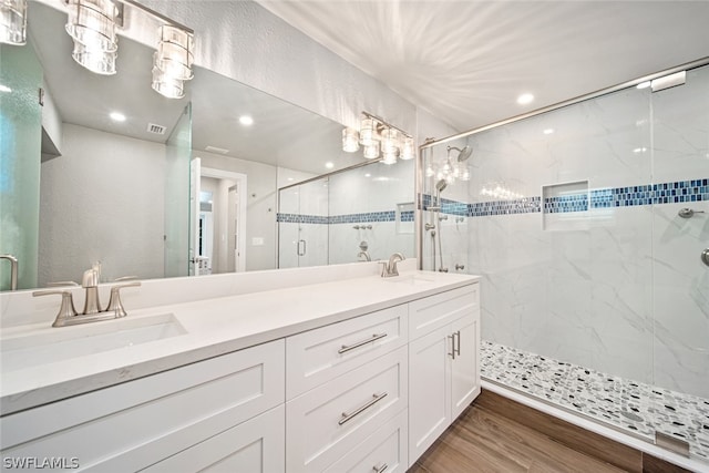 bathroom with hardwood / wood-style floors, double vanity, and a shower with door