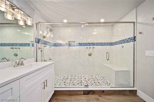 bathroom featuring hardwood / wood-style floors, walk in shower, and vanity with extensive cabinet space