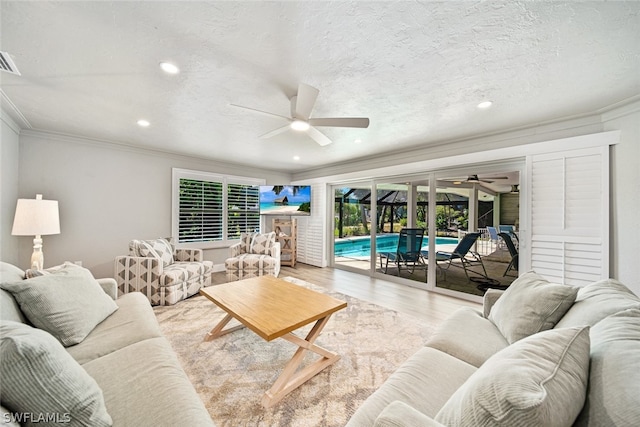 living room with hardwood / wood-style floors, ceiling fan, crown molding, and a textured ceiling