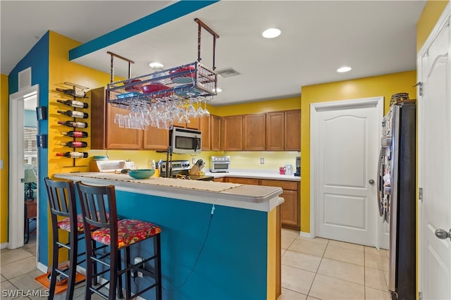 kitchen with kitchen peninsula, pendant lighting, stainless steel appliances, and light tile floors