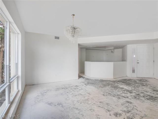 empty room with a wealth of natural light and a chandelier