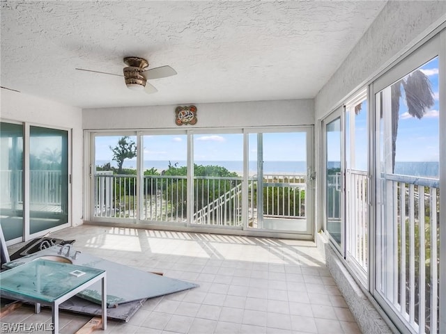 unfurnished sunroom with a water view and ceiling fan