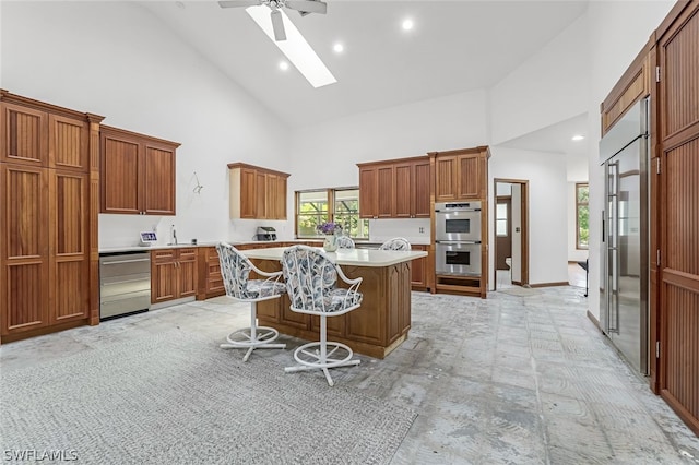 kitchen featuring a center island, stainless steel appliances, high vaulted ceiling, ceiling fan, and a skylight