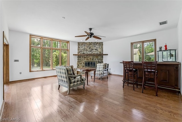 living area featuring hardwood / wood-style floors, ceiling fan, and a fireplace