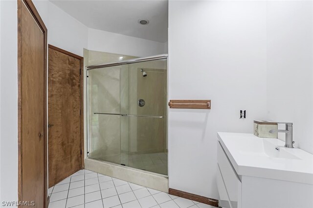 bathroom with tile flooring, vanity, and a shower with door