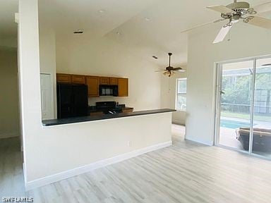 kitchen with vaulted ceiling, light hardwood / wood-style flooring, kitchen peninsula, ceiling fan, and fridge