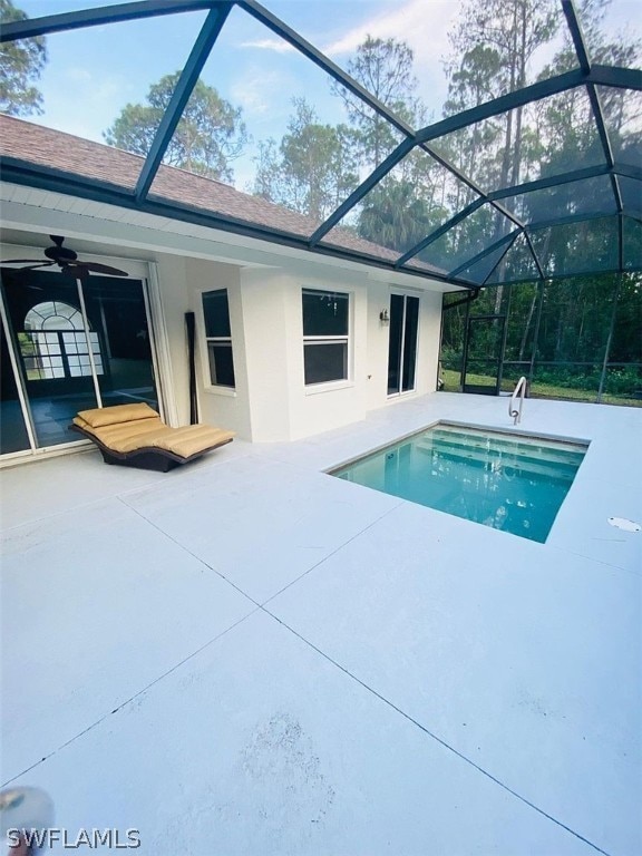 view of swimming pool featuring a patio, glass enclosure, and ceiling fan