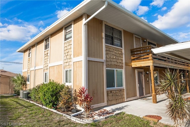 view of property exterior with a balcony, a patio, and central AC