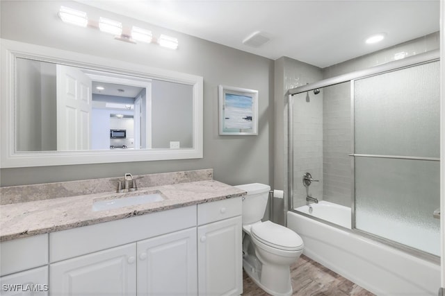 full bathroom featuring vanity, combined bath / shower with glass door, wood-type flooring, and toilet