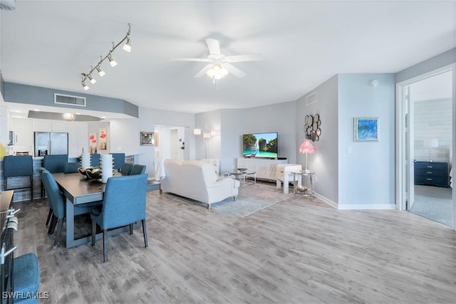 dining area with rail lighting, light hardwood / wood-style floors, and ceiling fan