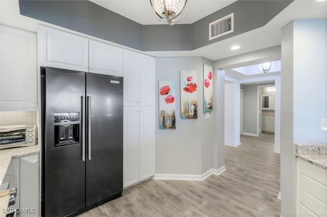 kitchen with light stone countertops, white cabinets, stainless steel refrigerator with ice dispenser, and light hardwood / wood-style flooring