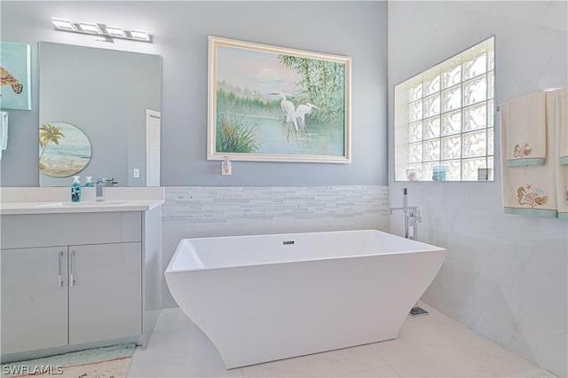 bathroom featuring tile walls, a soaking tub, a wainscoted wall, and vanity