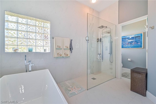 full bathroom featuring a freestanding bath, marble finish floor, a shower stall, and toilet