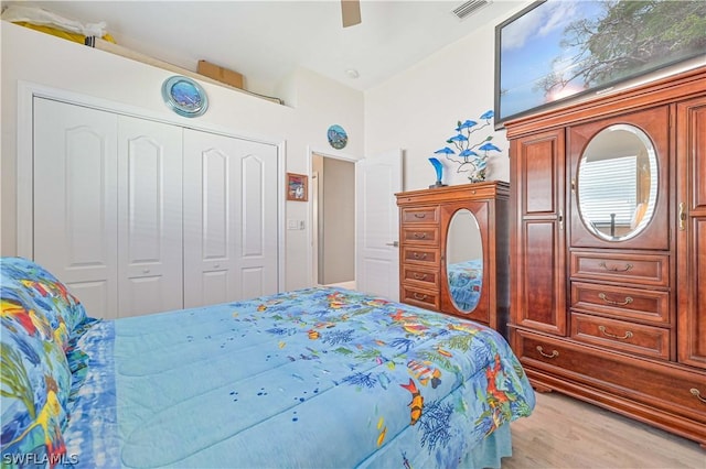 bedroom featuring light wood-style floors, a ceiling fan, visible vents, and a closet