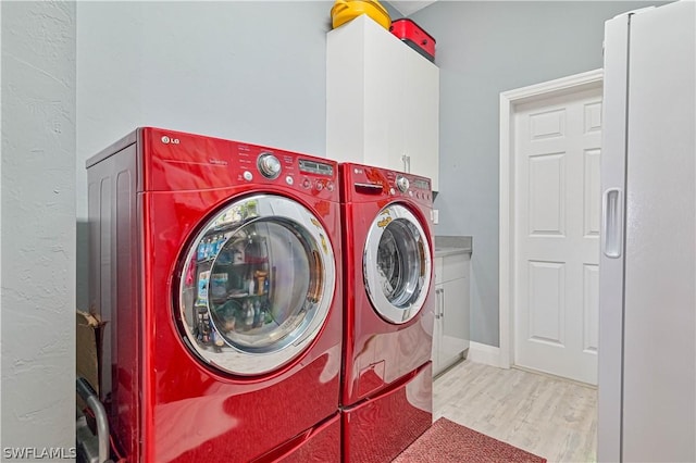 laundry area featuring baseboards, cabinet space, washing machine and clothes dryer, and wood finished floors