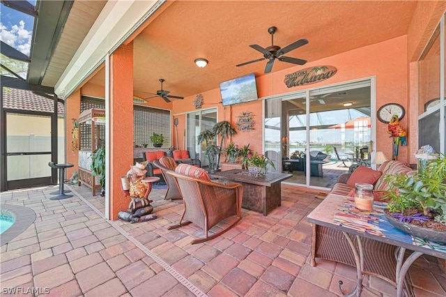 view of patio with a lanai, ceiling fan, and a fire pit