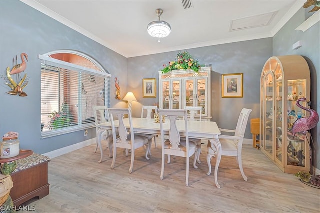 dining area featuring baseboards, visible vents, crown molding, and wood finished floors