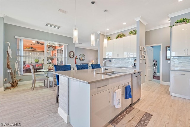 kitchen featuring light countertops, white cabinetry, a sink, light wood-type flooring, and dishwasher