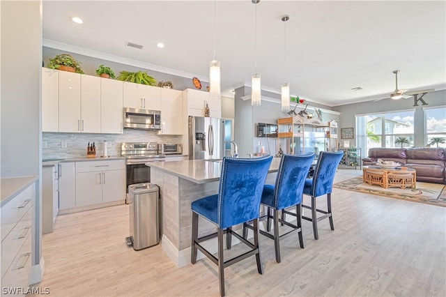 kitchen featuring ornamental molding, appliances with stainless steel finishes, a breakfast bar, and visible vents