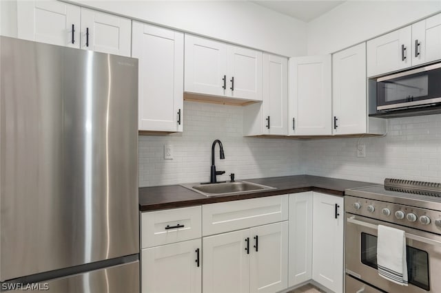 kitchen featuring tasteful backsplash, appliances with stainless steel finishes, white cabinets, and sink