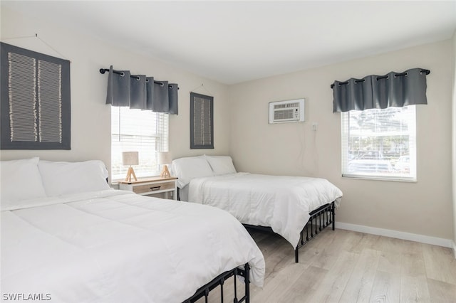 bedroom featuring a wall unit AC and light wood-type flooring