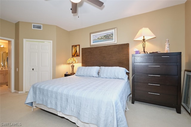 bedroom featuring light colored carpet, ceiling fan, connected bathroom, and a closet