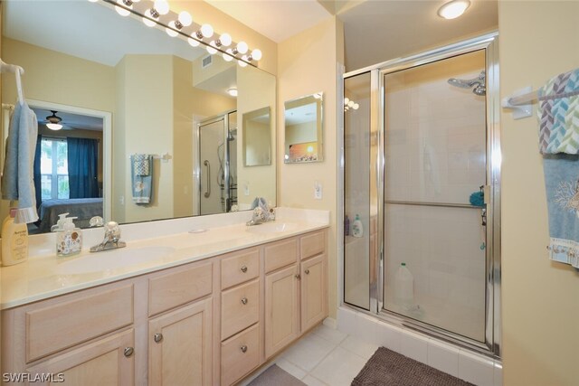 bathroom featuring tile flooring, ceiling fan, dual sinks, oversized vanity, and a shower with shower door