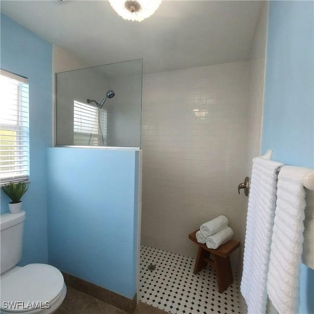 bathroom featuring a tile shower, tile patterned flooring, plenty of natural light, and toilet