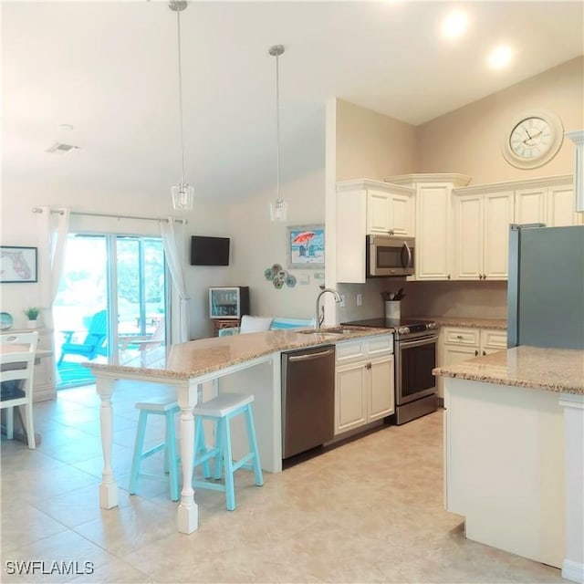 kitchen featuring pendant lighting, lofted ceiling, stainless steel appliances, light stone counters, and white cabinets