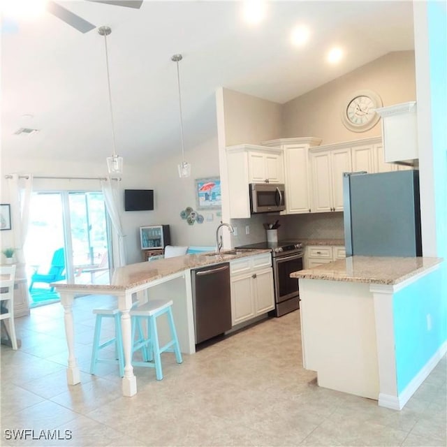 kitchen with white cabinets, backsplash, hanging light fixtures, stainless steel appliances, and light stone countertops