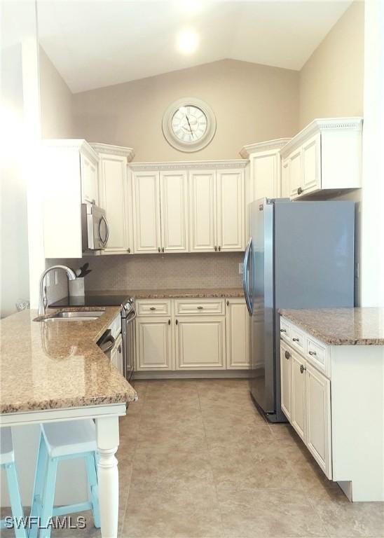 kitchen with white cabinetry, sink, kitchen peninsula, stainless steel appliances, and light stone countertops