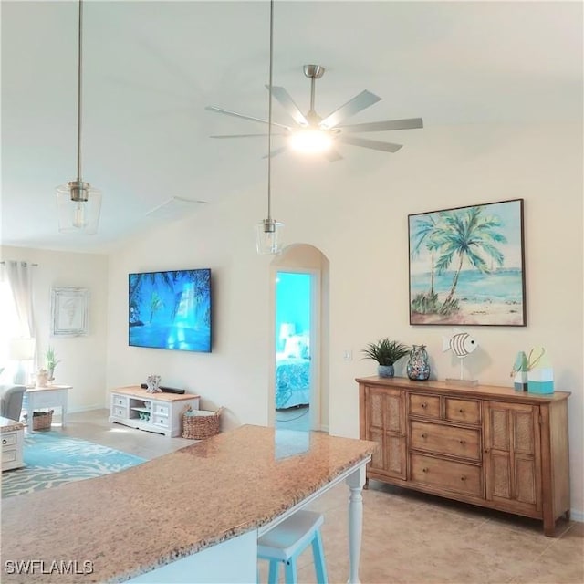 kitchen with ceiling fan, a breakfast bar, pendant lighting, and light stone counters