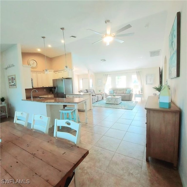 dining space with sink, light tile patterned floors, and ceiling fan