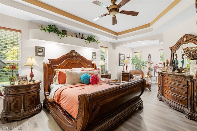 bedroom featuring hardwood / wood-style flooring, ceiling fan, and a raised ceiling