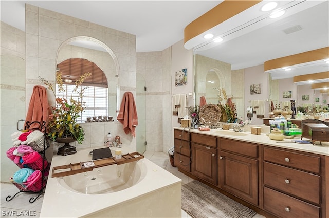 bathroom featuring tile walls, vanity, tile floors, and a bath to relax in