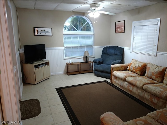 living room featuring a drop ceiling, ceiling fan, and light tile floors