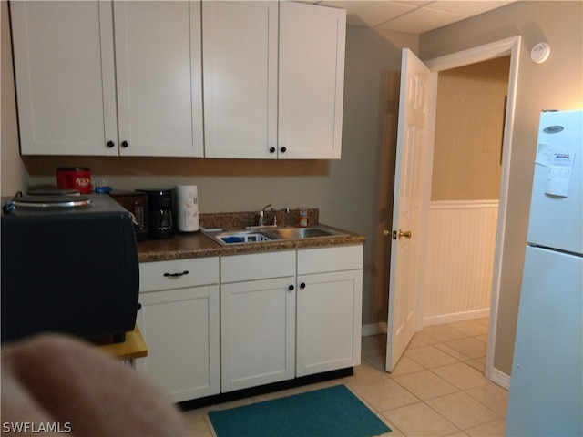 kitchen featuring sink, white cabinetry, white fridge, and light tile floors