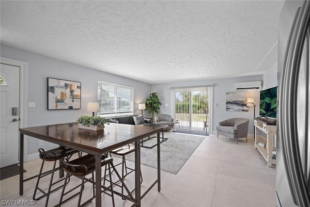 tiled dining space featuring a wall mounted AC and a textured ceiling